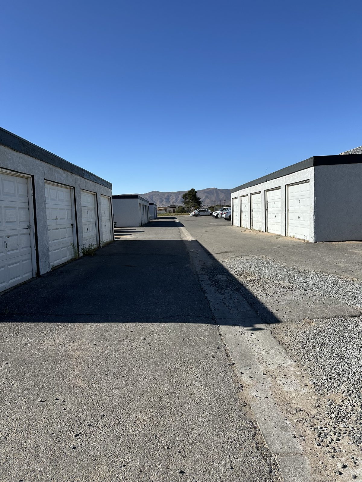 The row of private garages in the front lot, white overhead doors on a grey block building, with the townhomes and mountains beyond.